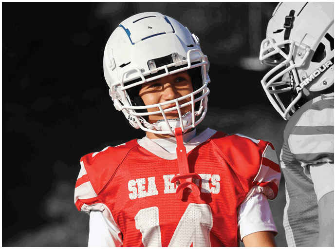Three football players in blue and white uniforms running on a field. Description generated by AI