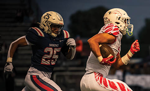 Two men wearing football uniforms are hugging each other on a field. AI generated content