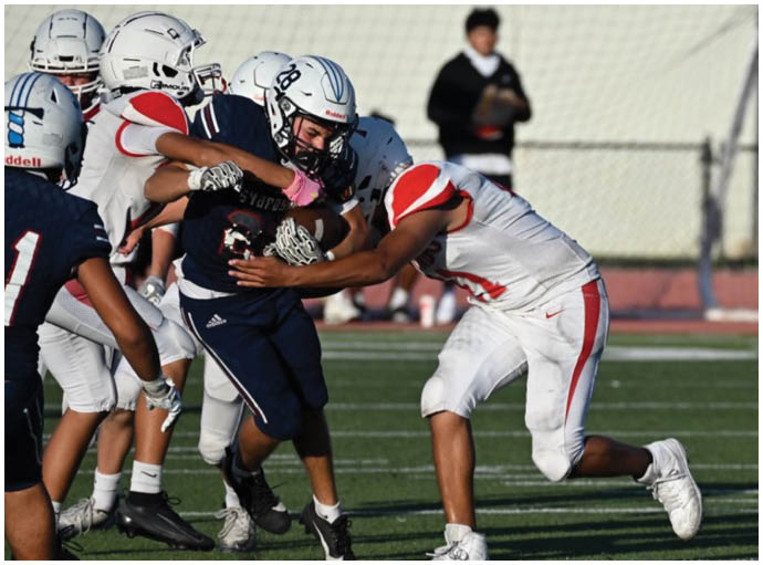 Three football players in blue and white uniforms running on a field. Description generated by AI