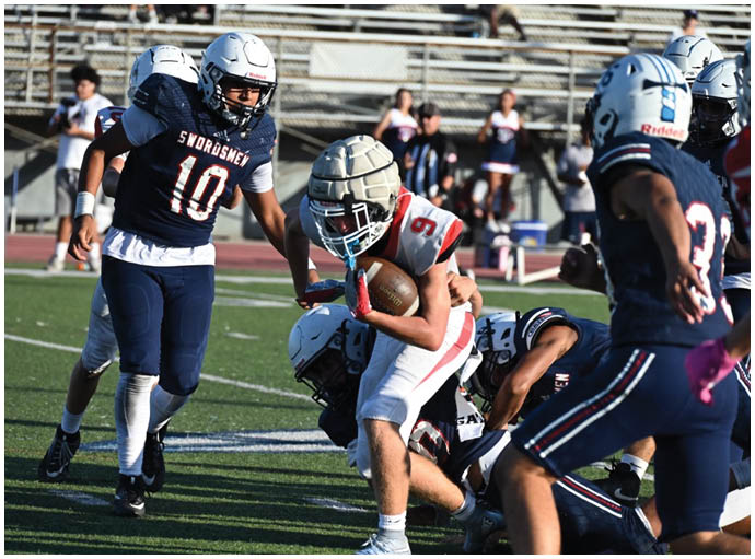 Three football players in blue and white uniforms running on a field. Description generated by AI