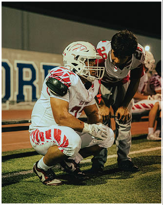 A football game is taking place with a group of men on the field. Description generated by AI