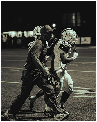 A football game is taking place with a group of men on the field. Description generated by AI