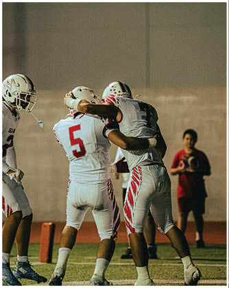 A football game is taking place with a group of men on the field. Description generated by AI