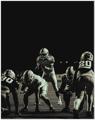 A football game is taking place with a group of men on the field. Description generated by AI