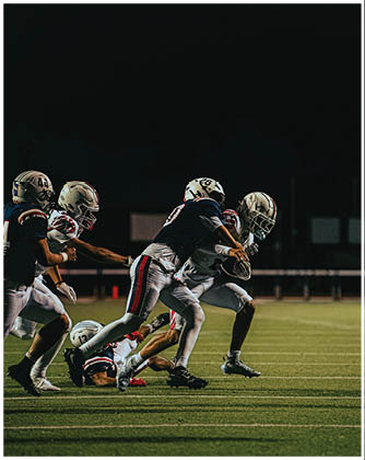 A football game is taking place with a group of men on the field. Description generated by AI