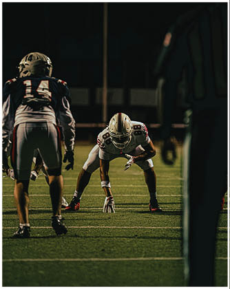A football game is taking place with a group of men on the field. Description generated by AI