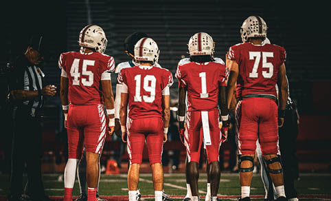 Two men wearing football uniforms are hugging each other on a field. AI generated content
