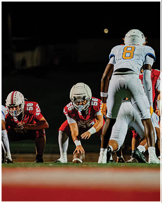A football game is taking place with a group of men on the field. Description generated by AI