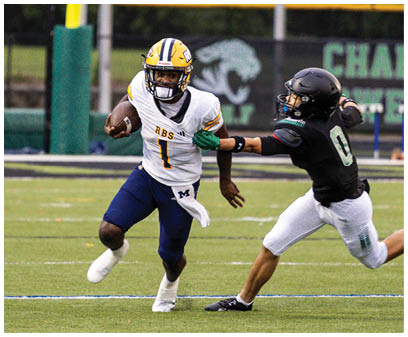 Two people wearing football helmets and uniforms are engaged in a play on a football field near a yellow goalpost. Description generated by AI
