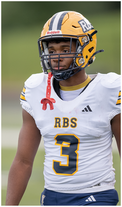 A person wearing a yellow and white football helmet and a white football jersey with the number 3 and the letters RBS stands on a field. Description generated by AI