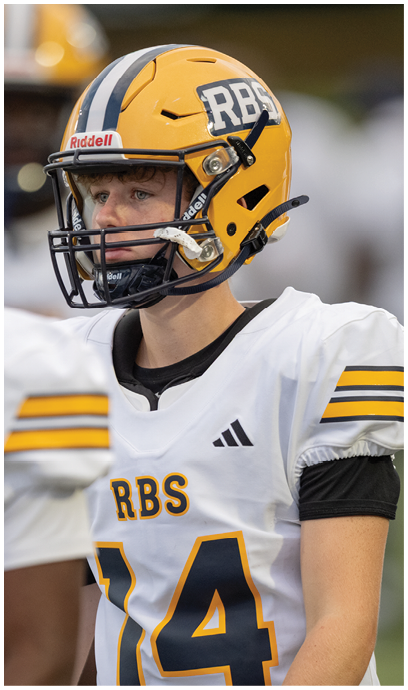 A person wearing a yellow football helmet and white jersey with the number 14 and the letters RBS is standing next to another person in similar attire. Description generated by AI