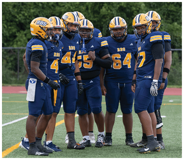 A group of six people wearing blue and yellow football uniforms and helmets are standing together on a sports field. Description generated by AI