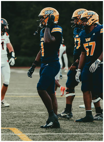 Three people in blue and yellow football uniforms stand on a field facing a person in a white uniform during a game. Description generated by AI