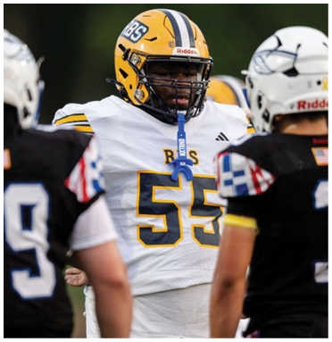 A person wearing a yellow helmet and white football jersey with the number 55 stands facing two people in black football jerseys and white helmets on a field. Description generated by AI