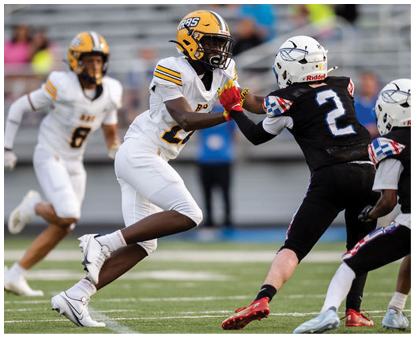 Two people in white football uniforms are engaged with two people in black football uniforms on a field during a game. Description generated by AI