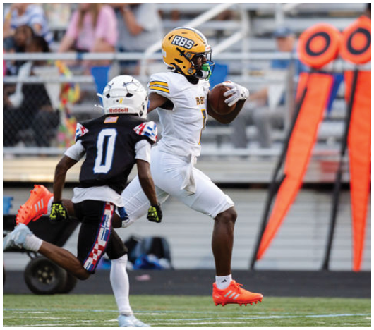 A person in a white football uniform and yellow helmet is running with the ball while being chased by another person in a black uniform on a football field. Description generated by AI