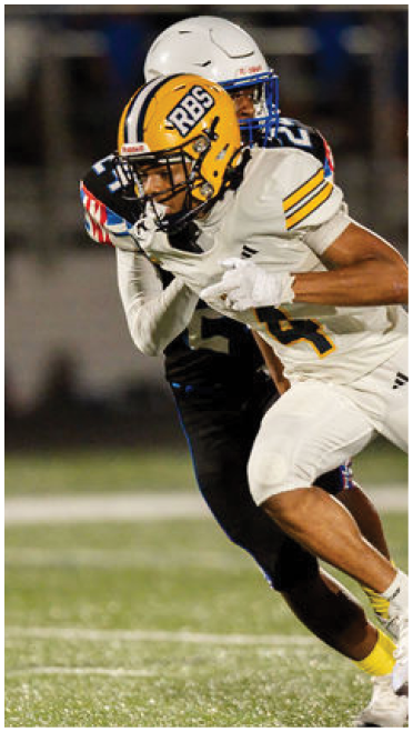 Two people in football uniforms with yellow helmets are engaged in a play on a football field. Description generated by AI