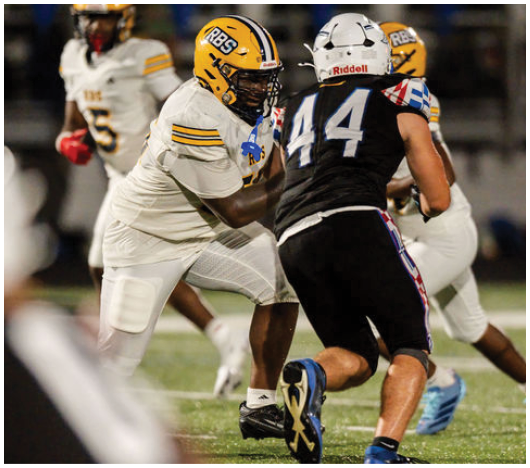 Two people in football uniforms are engaged in a play on a field with one person in white and yellow gear facing another in black and white gear. Description generated by AI