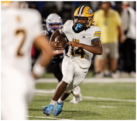 A person wearing a yellow and white football uniform with the number 14 is running on a field while holding a football, with another player and a blurred figure in the background. Description generated by AI