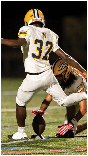 A person wearing a white football jersey with the number 3 and a yellow helmet is extending their arm against a dark background. Description generated by AI