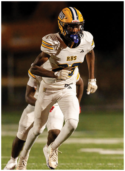 A person wearing a yellow and blue football helmet and white uniform with “RBS" on the chest is running on a football field during a game. Description generated by AI