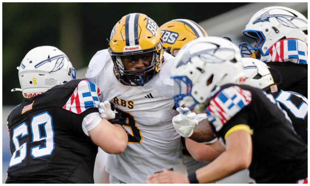 Several people wearing football helmets and uniforms are engaged in a close physical play on a football field. Description generated by AI
