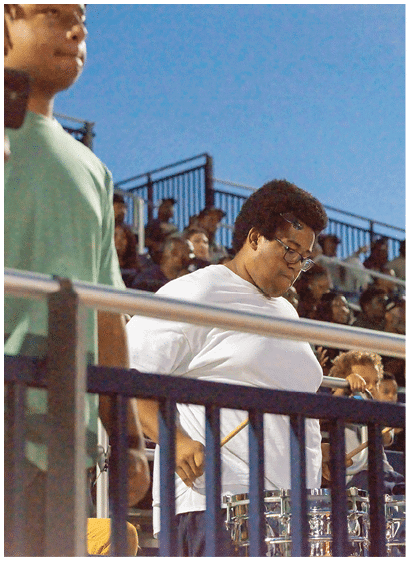 A person wearing a white sports polo shirt with a logo and an Adidas emblem is standing outdoors. Description generated by AI