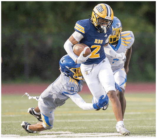 A person wearing a blue and yellow football uniform with the number 57 is running on a field with other players blurred in the background. Description generated by AI