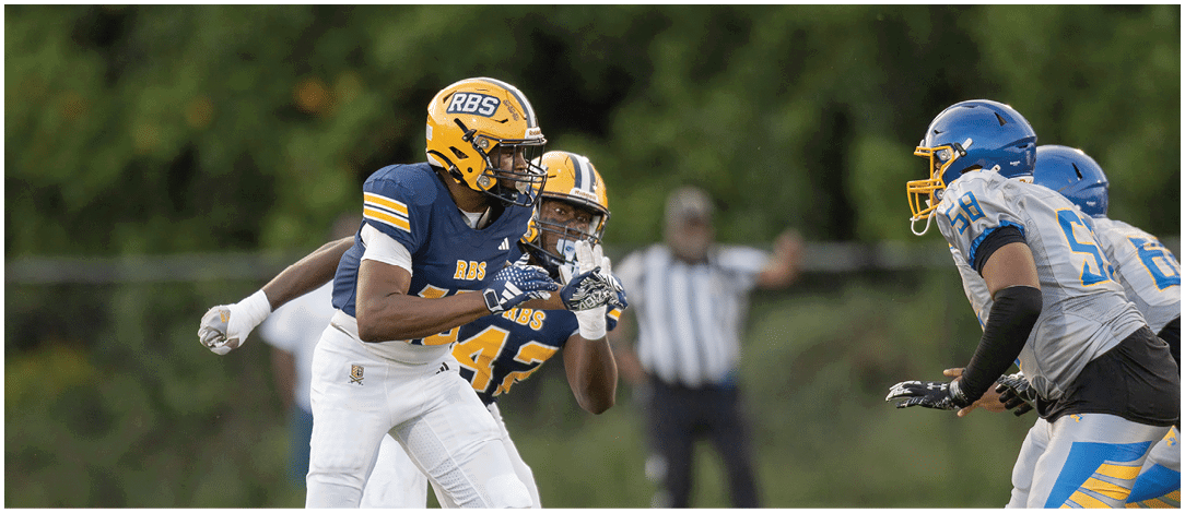 A person wearing a blue and yellow football uniform with the number 57 is running on a field with other players blurred in the background. Description generated by AI
