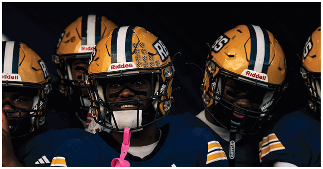 Four yellow sports helmets with blue and white stripes are partially visible against a dark background. Description generated by AI
