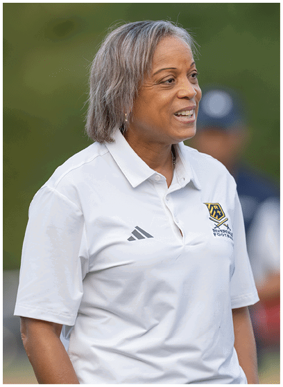 A person wearing a white sports polo shirt with a logo and an Adidas emblem is standing outdoors. Description generated by AI