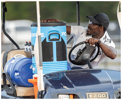 A close-up view of the front part of a dark blue EZGO vehicle with a partially visible orange and blue container in the background. Description generated by AI