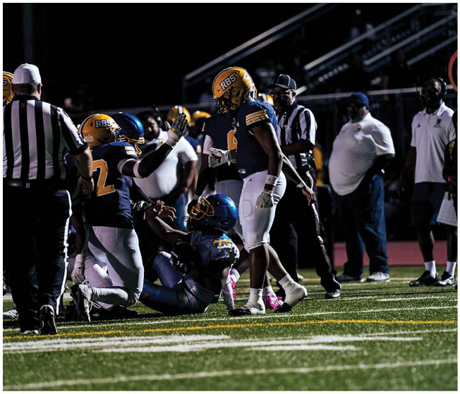 People in football uniforms are celebrating on a field at night while referees and coaches observe nearby. Description generated by AI