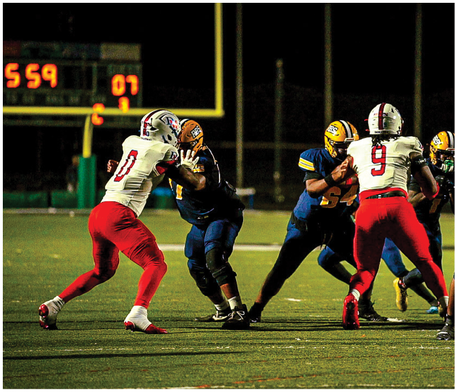 A group of people wearing football helmets and uniforms are gathered on a field under a dark night sky with a bright moon visible above. Description generated by AI