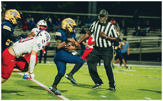 A person wearing a yellow and blue football helmet and uniform is standing outdoors under a partly cloudy sky. Description generated by AI