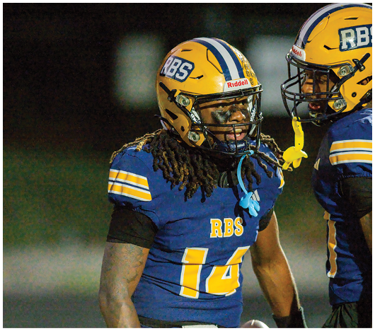 Two people wearing yellow football helmets with black and white stripes are standing against a dark night sky. Description generated by AI