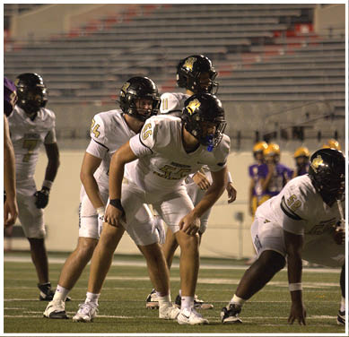 A group of football players huddled together on the field. Description generated by AI