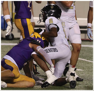 A group of football players huddled together on the field. Description generated by AI