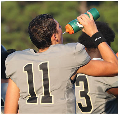 A group of football players huddled together on the field. Description generated by AI