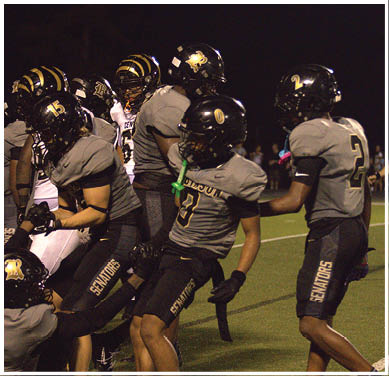 A group of football players huddled together on the field. Description generated by AI
