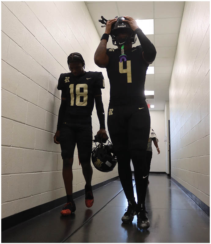 A group of football players wearing black and white uniforms. Description generated by AI