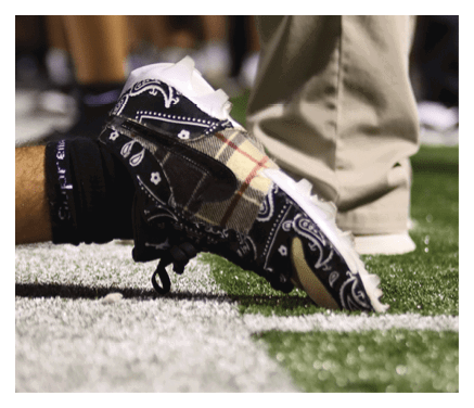 A man in a black jersey is running on a field with a football in his hand. AI generated content