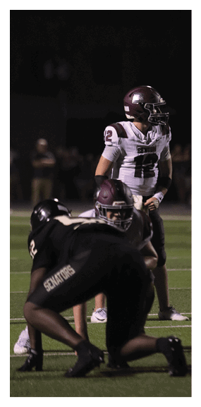 A football player is kneeling on the field, wearing a green jersey and a helmet. AI generated content