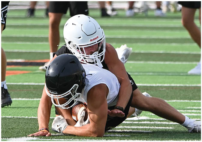 A group of football players wearing black and white uniforms. Description generated by AI