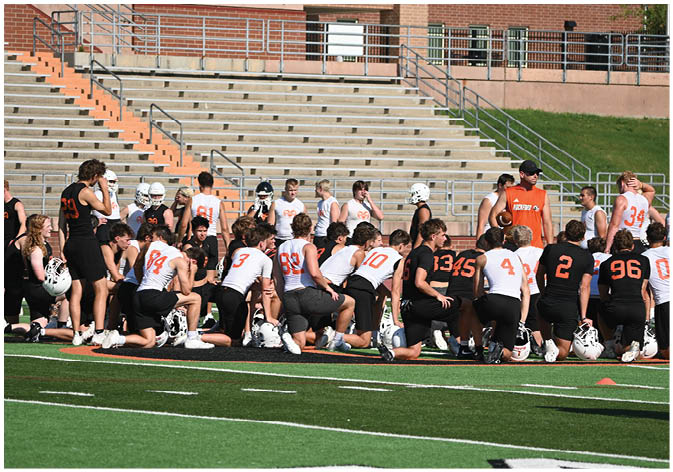 A group of football players wearing black and white uniforms. Description generated by AI