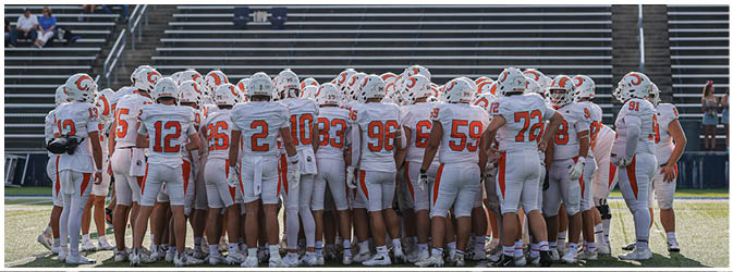 A football game is taking place on a field with players wearing blue and white uniforms. Description generated by AI