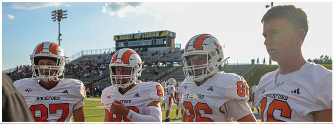 A football game is taking place on a field with players wearing blue and white uniforms. Description generated by AI