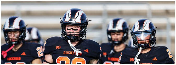 A football game is taking place on a field with players wearing blue and white uniforms. Description generated by AI