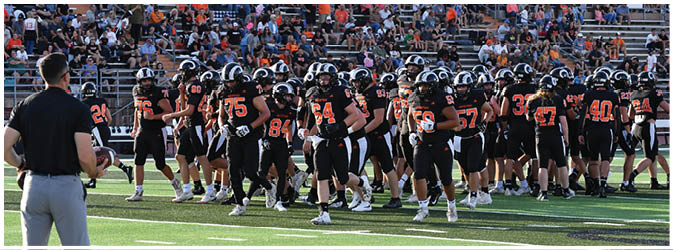A football game is taking place on a field with players wearing blue and white uniforms. Description generated by AI