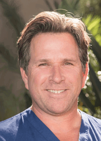 A close-up of a smiling person with short, neatly styled hair and light facial stubble. Description generated by AI